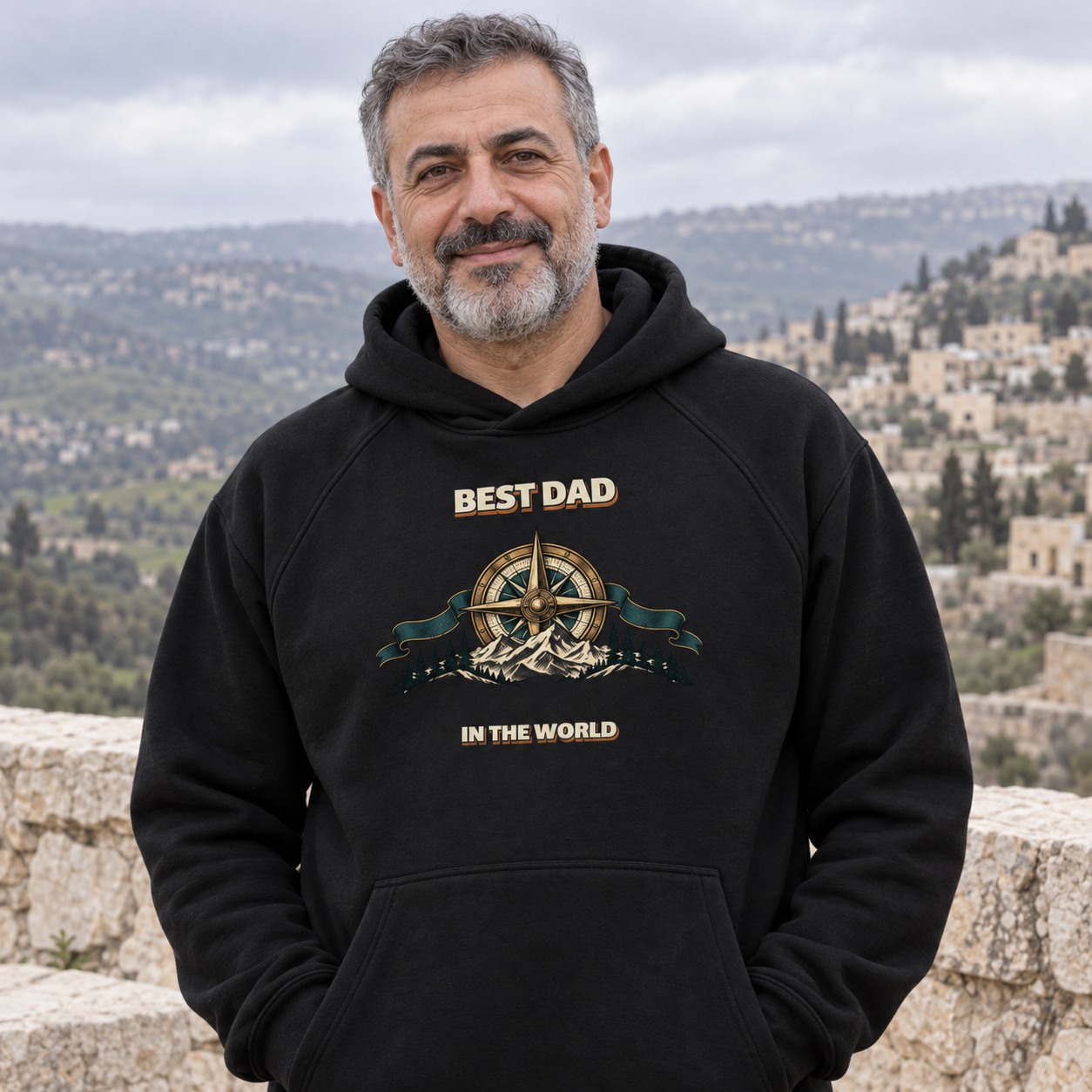 Black hoodie a bronze compass and mountains between Best Dad and In the World lettering