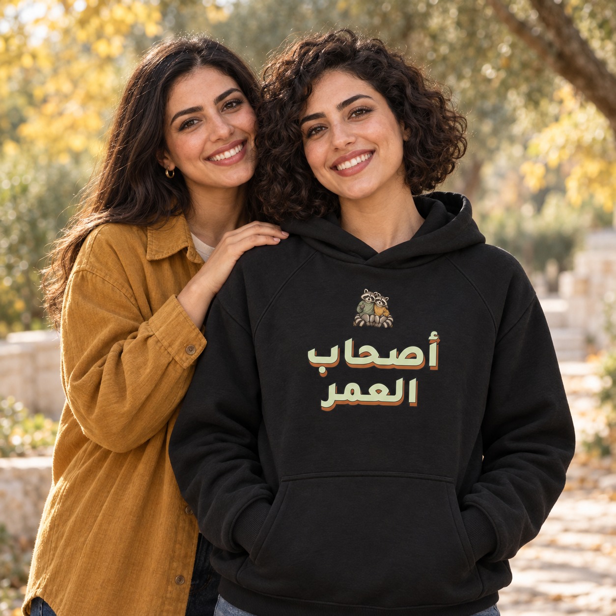 هودي أسود صديقان من الراكون فوق عبارة أصحاب العمر الكبيرة بالأخضر المريمي الفاتح وظل صلب دافئ