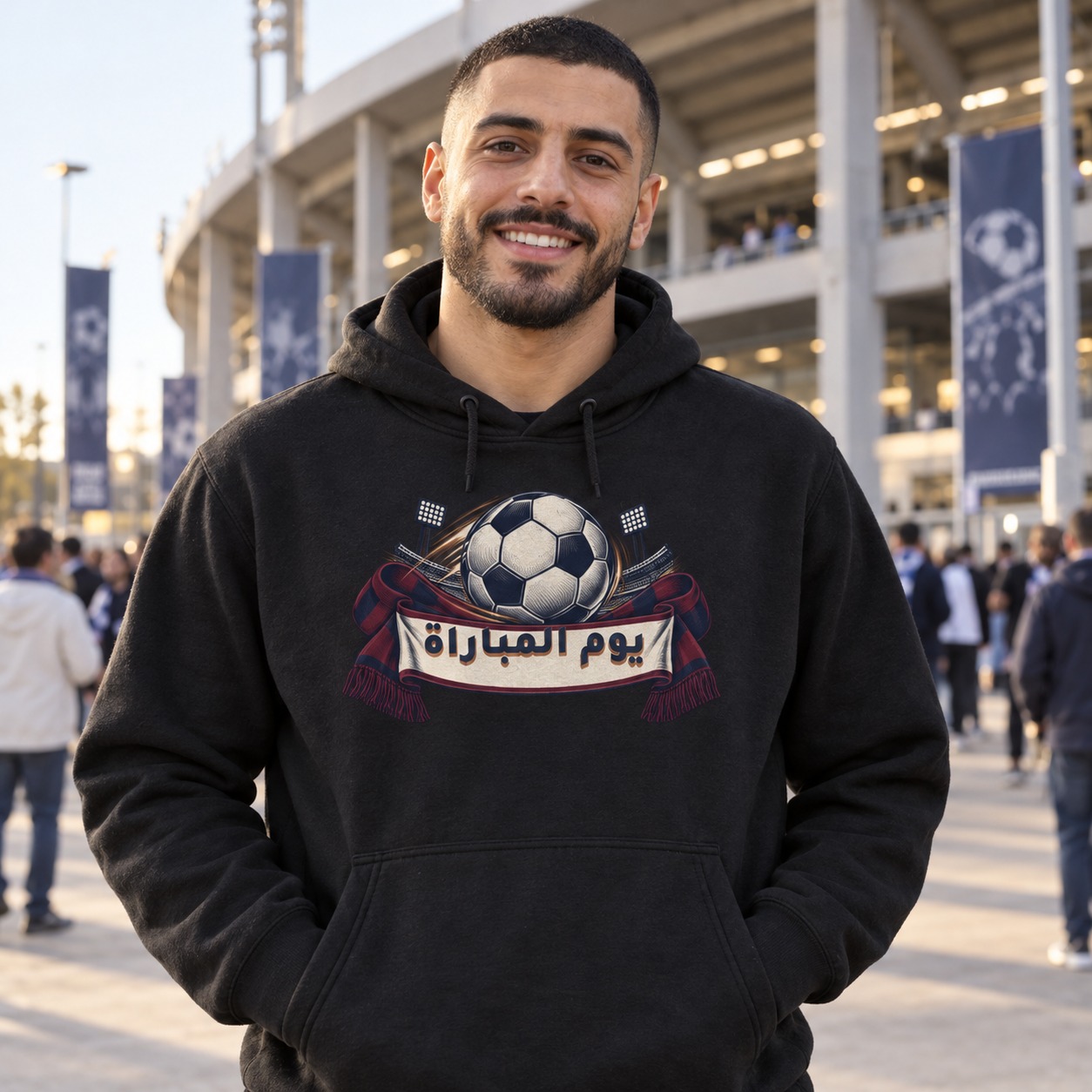 هودي أسود كرة قدم كبيرة أمام أضواء ومدرجات ووشاح تشجيع كحلي وخمري يحمل يوم المباراة بخط كحلي وظل نحاسي داخل وسط فاتح