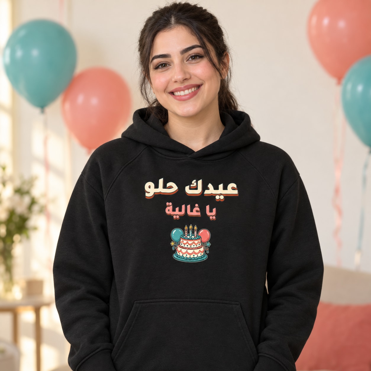 هودي أسود عيدك حلو وإهداء يا غالية بخط بارز فوق كعكة وبالونات
