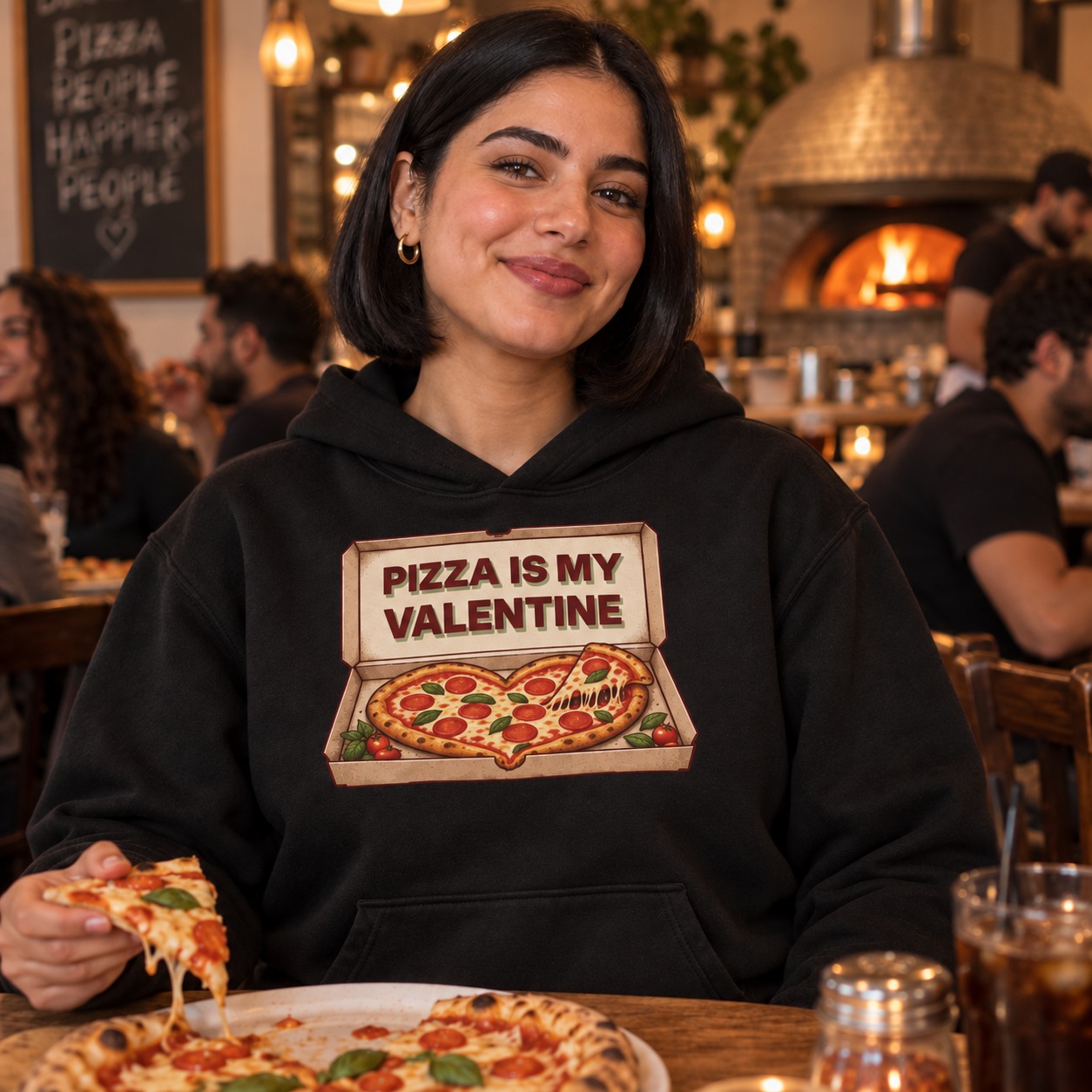 Black hoodie a golden heart-shaped pizza with a lifted cheese-pull slice in an open takeaway box, burgundy PIZZA IS MY VALENTINE lettering and sage solid shadow inside the ivory lid